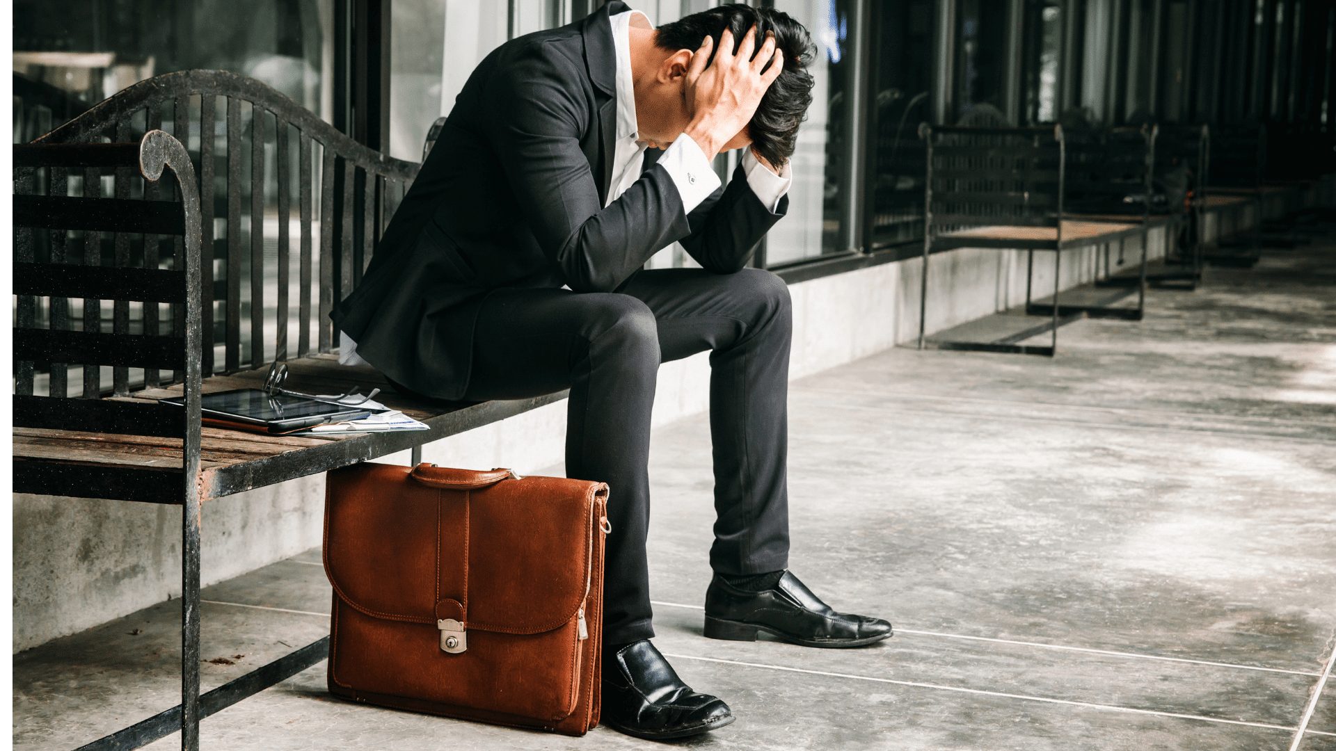 ベンチで頭を抱え込むサラリーマン