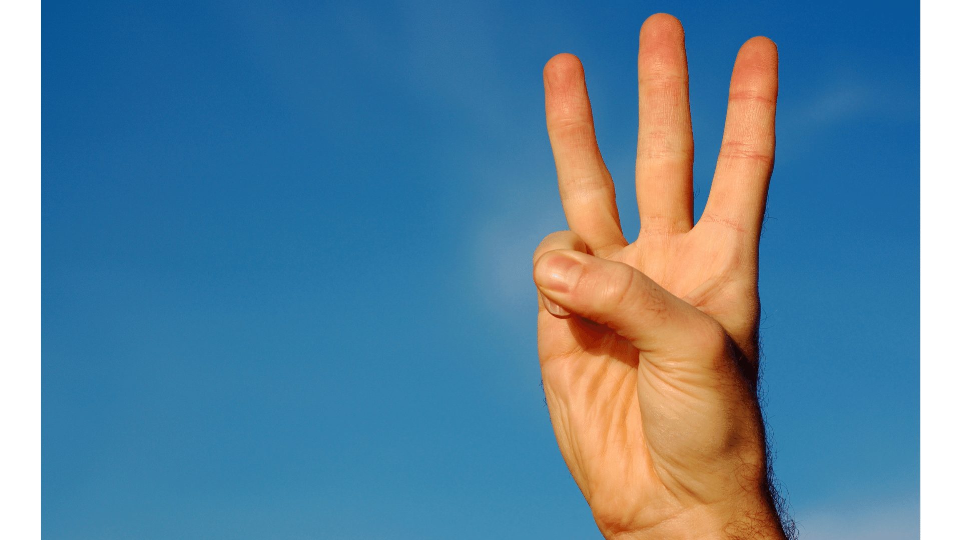 数字の３を指で示している写真